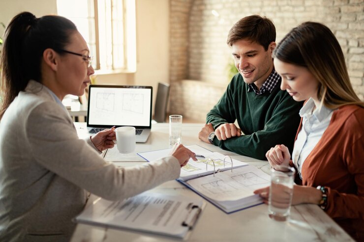 smiling-couple-insurance-agent-going-through-real-estate-plans-meeting-office-focus-is-man_637285-2808